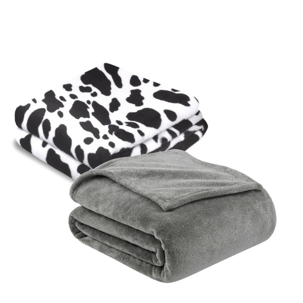 weiße mit schwarzen Flecken und anthrazite Kuscheldecke, dekorativ gefaltet vor weißem Hintergrund